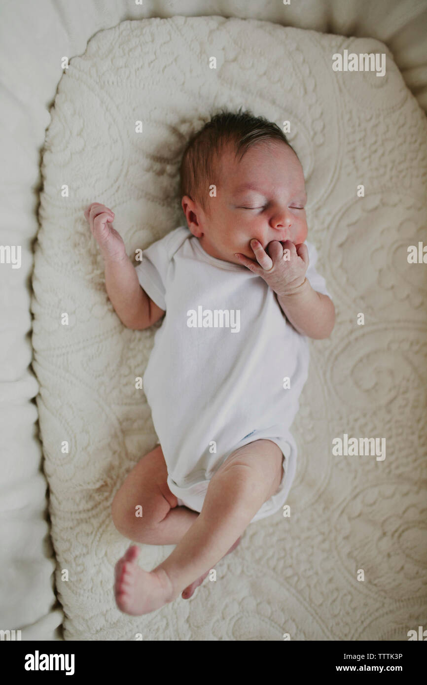 Overhead view of baby girl sleeping with hand in mouth on crib Stock