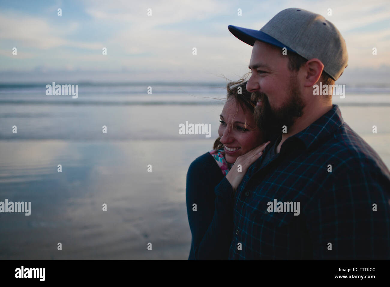 Cheerful couple standing at beach against sky Stock Photo