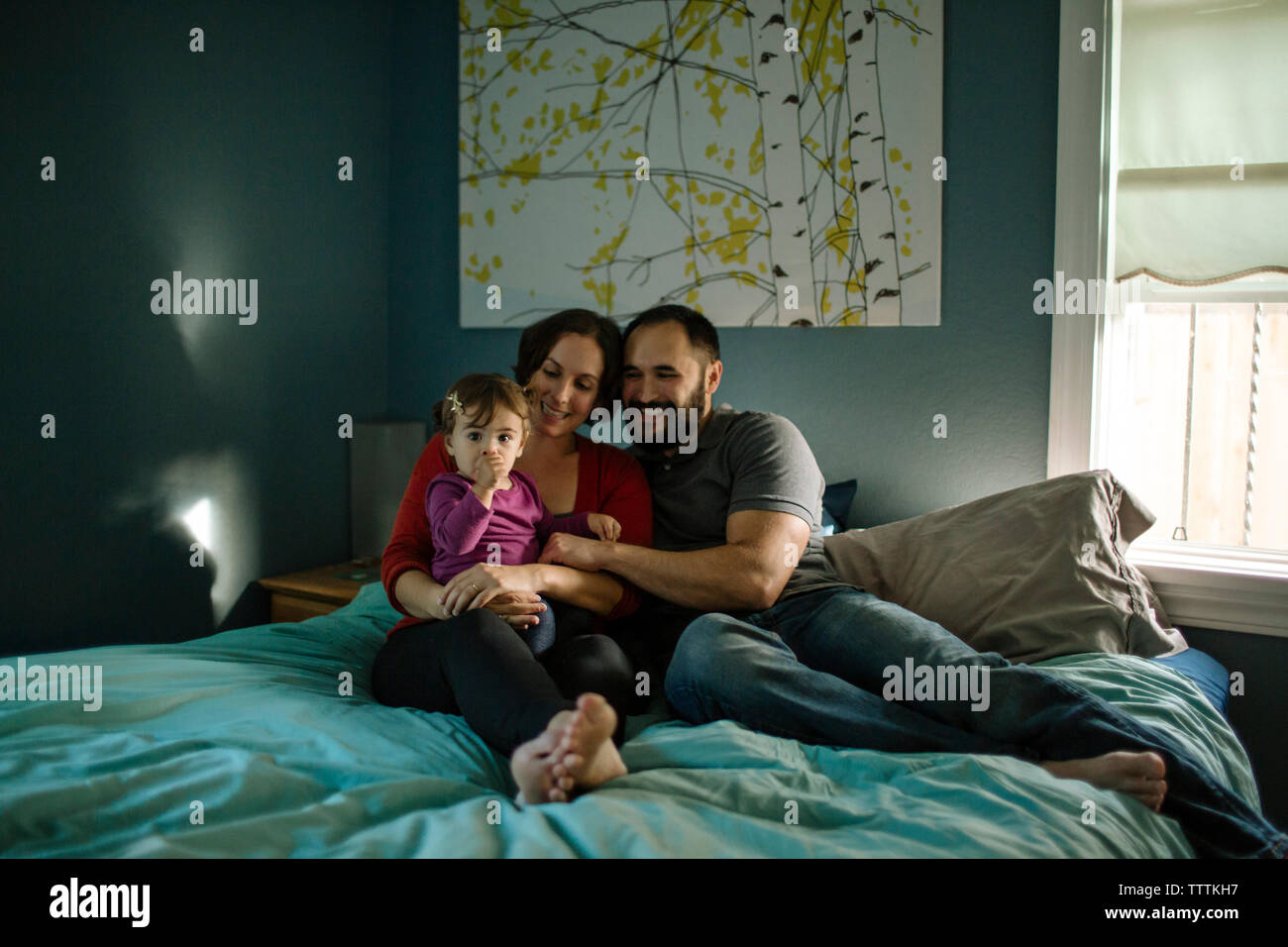 Portrait of daughter with father and mother on bed Stock Photo