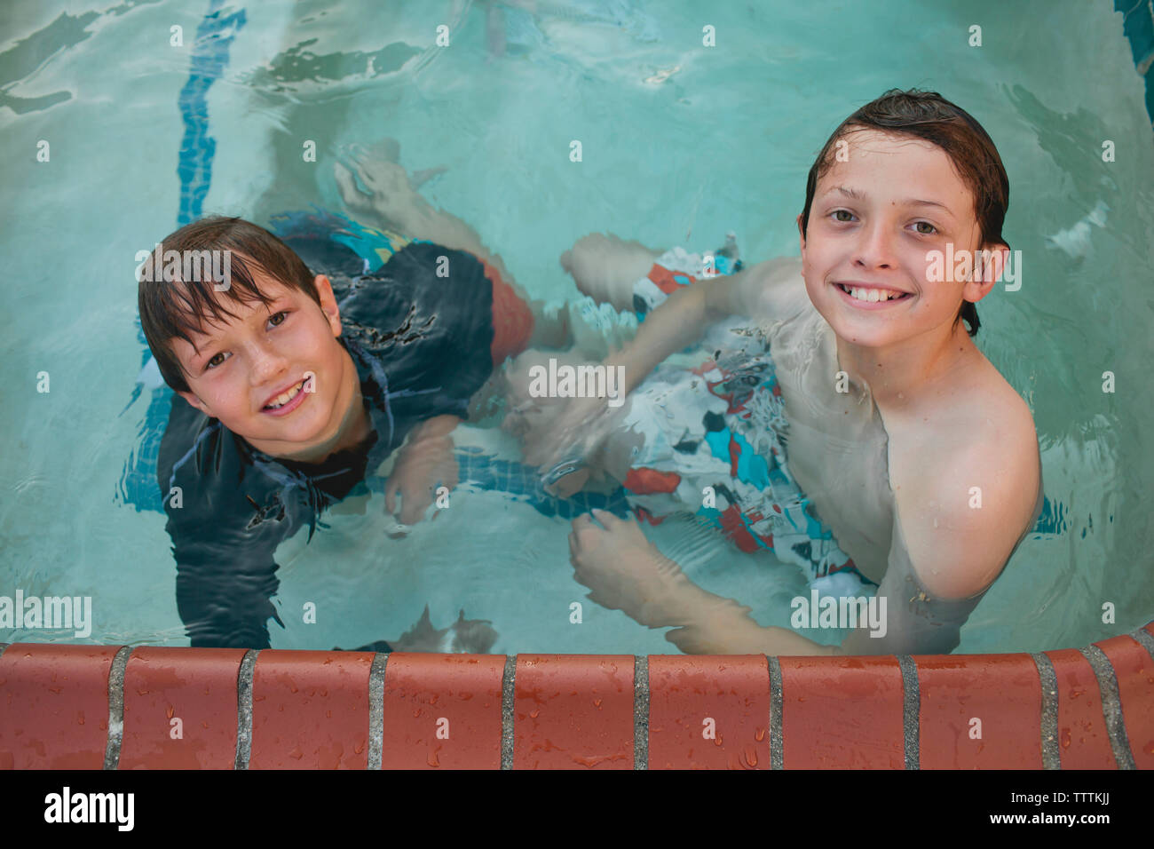 High angle portrait of happy brothers swimming in pool Stock Photo - Alamy