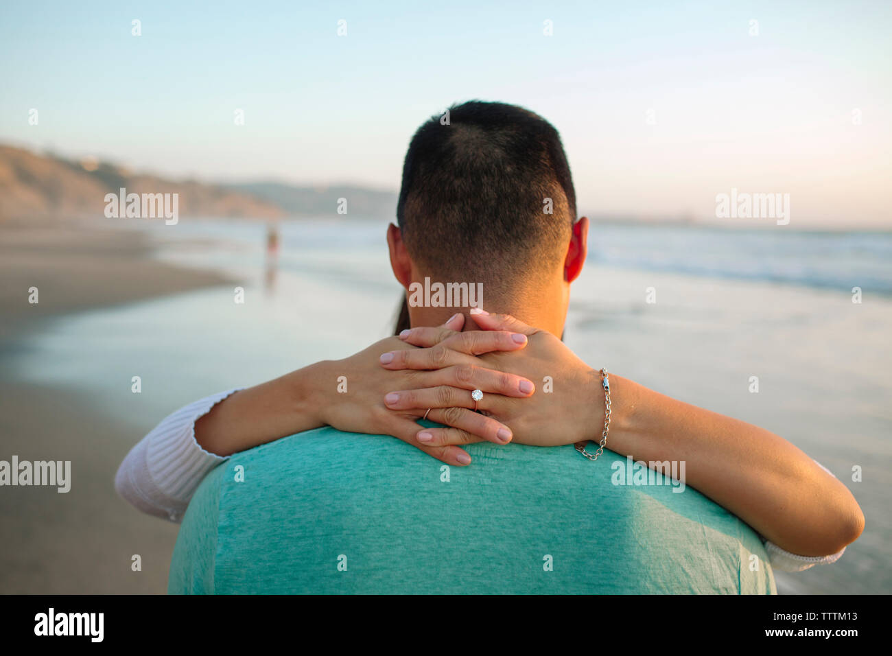 Close-up of girlfriend embracing boyfriend with hands clasped at beach Stock Photo