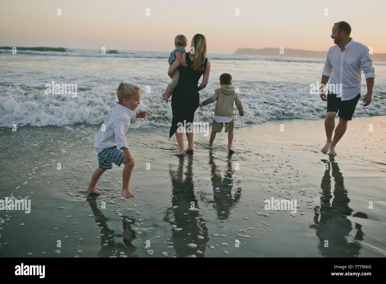 Family enjoying at beach during sunset Stock Photo