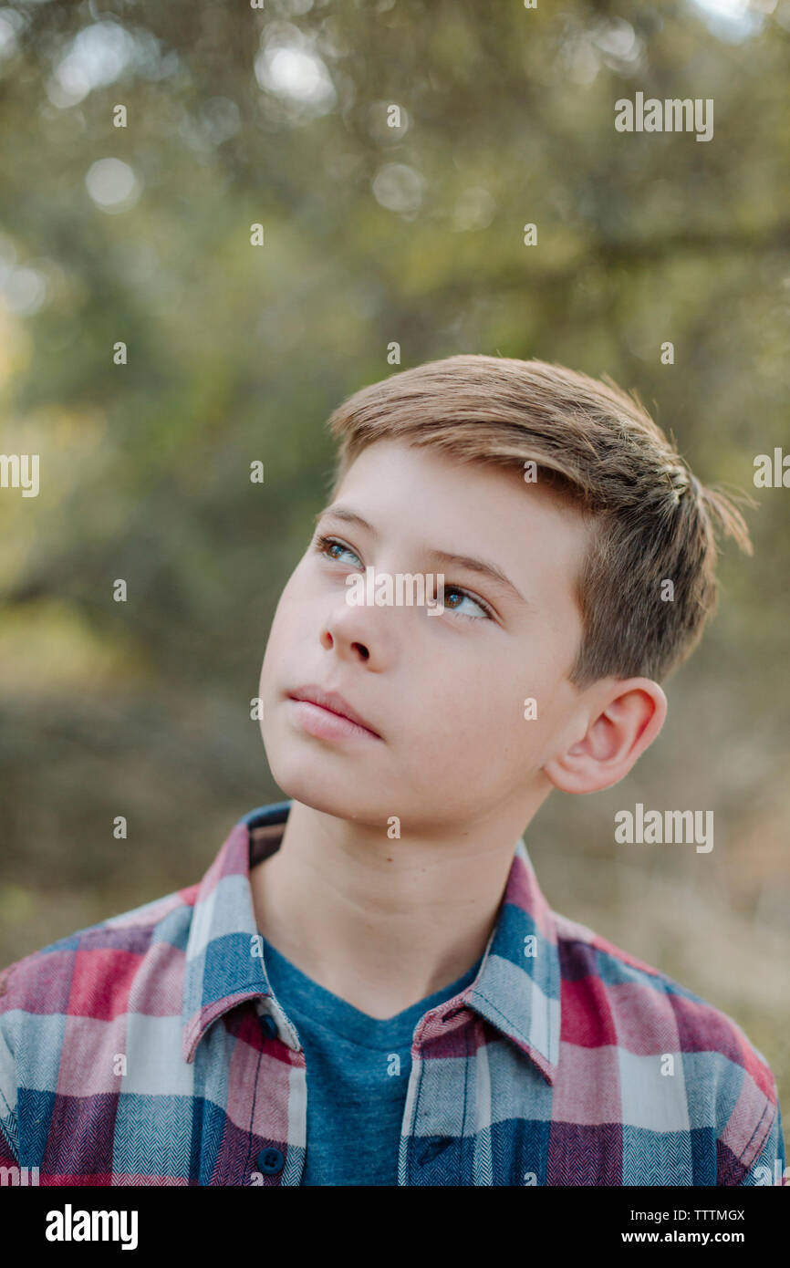 Close-up of thoughtful boy looking away while standing at park Stock Photo