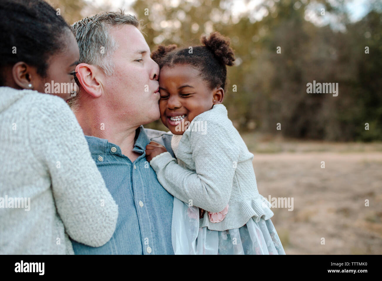 Father carrying daughters while standing at park Stock Photo - Alamy