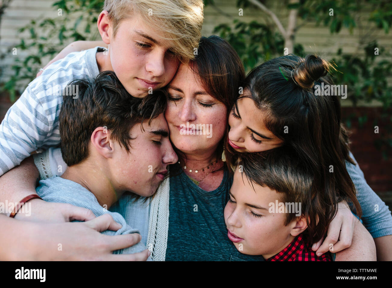 Close-up of children embracing mother with standing at yard Stock Photo