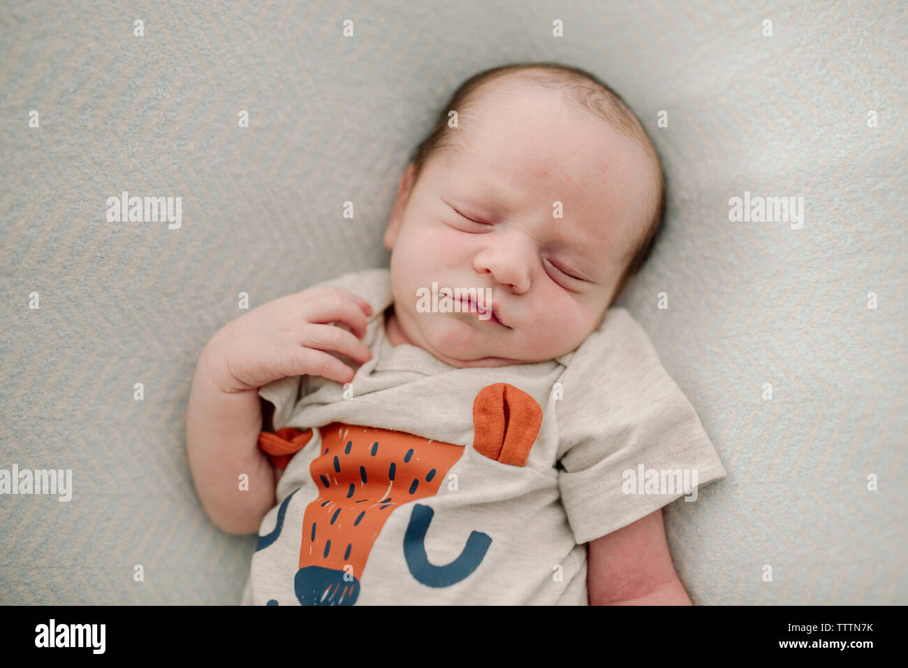 Overhead view of cute newborn baby boy sleeping on bed at home Stock