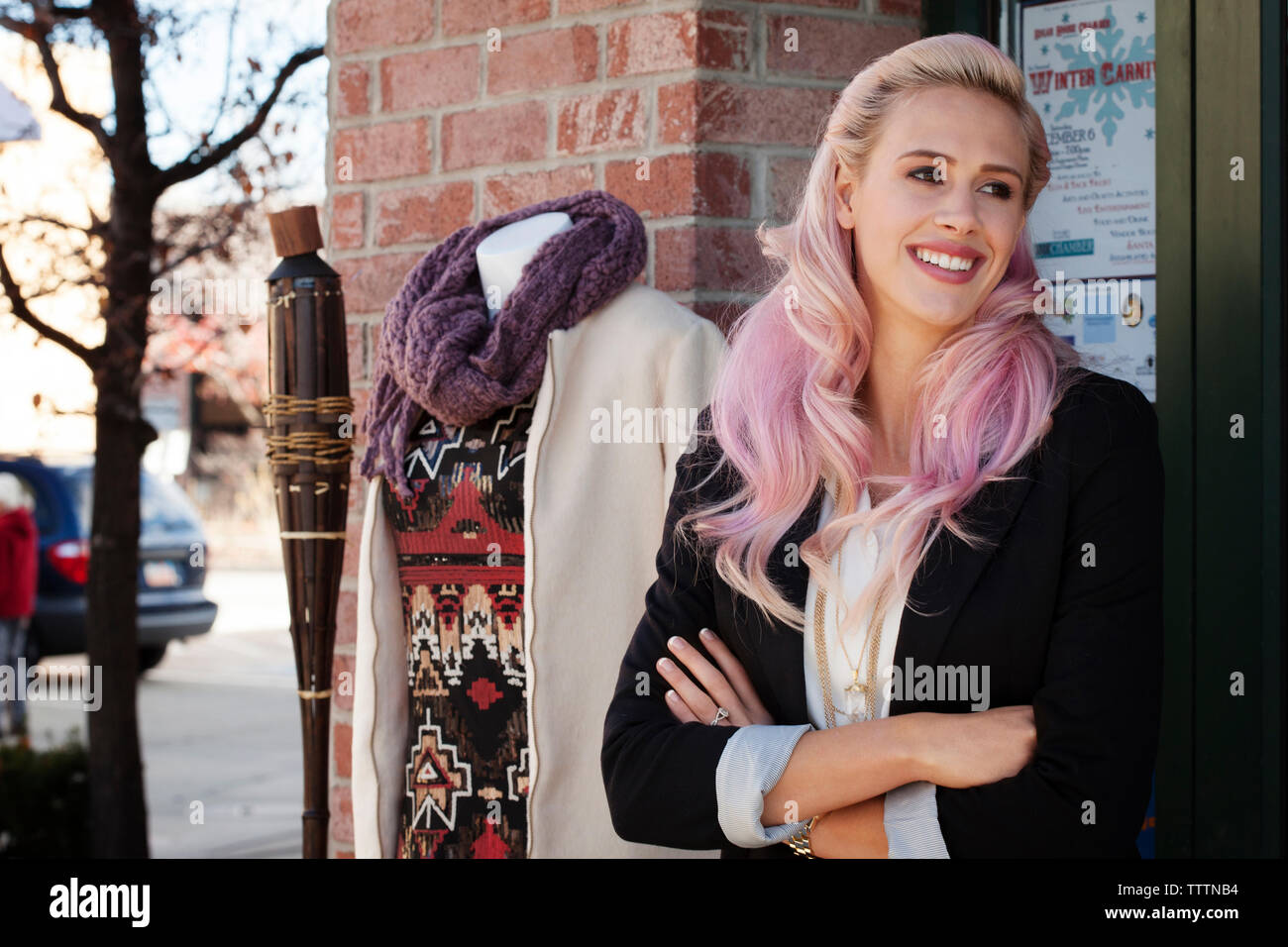Young female owner with arms crossed looking away while standing by mannequin Stock Photo