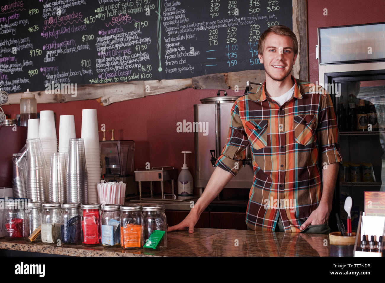 Portrait of owner standing at counter of coffee shop Stock Photo