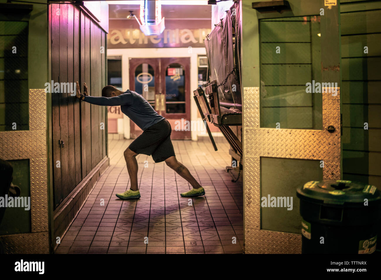Man exercising at passage with store in background Stock Photo