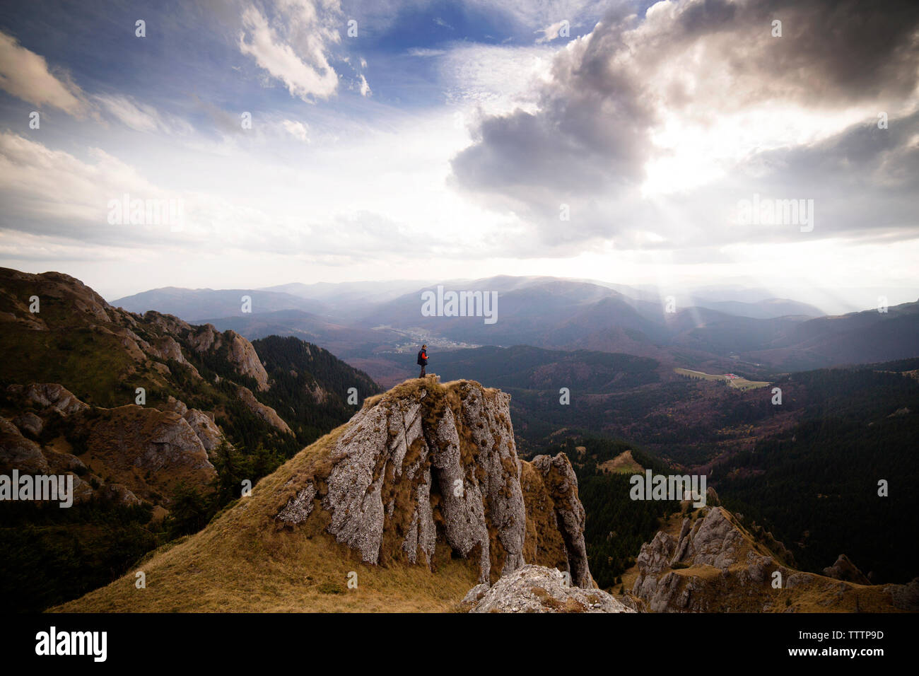 Man standing on cliff against cloudy sky Stock Photo