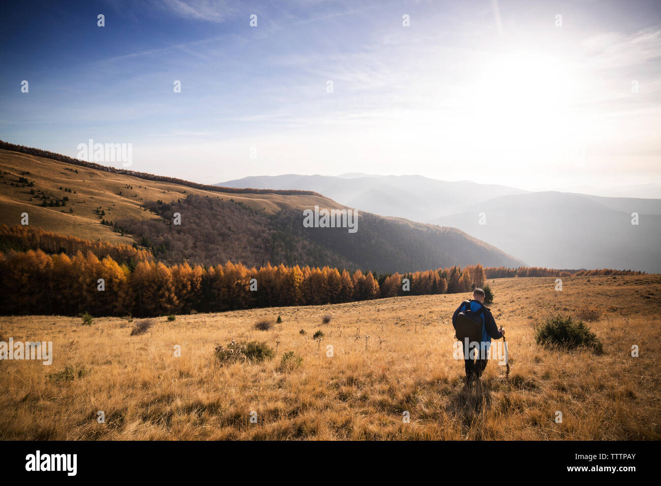 Male backpacker walking on mountain against sky Stock Photo