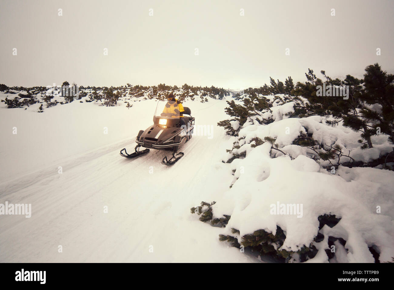 Man driving snowmobile on snowy field against sky Stock Photo