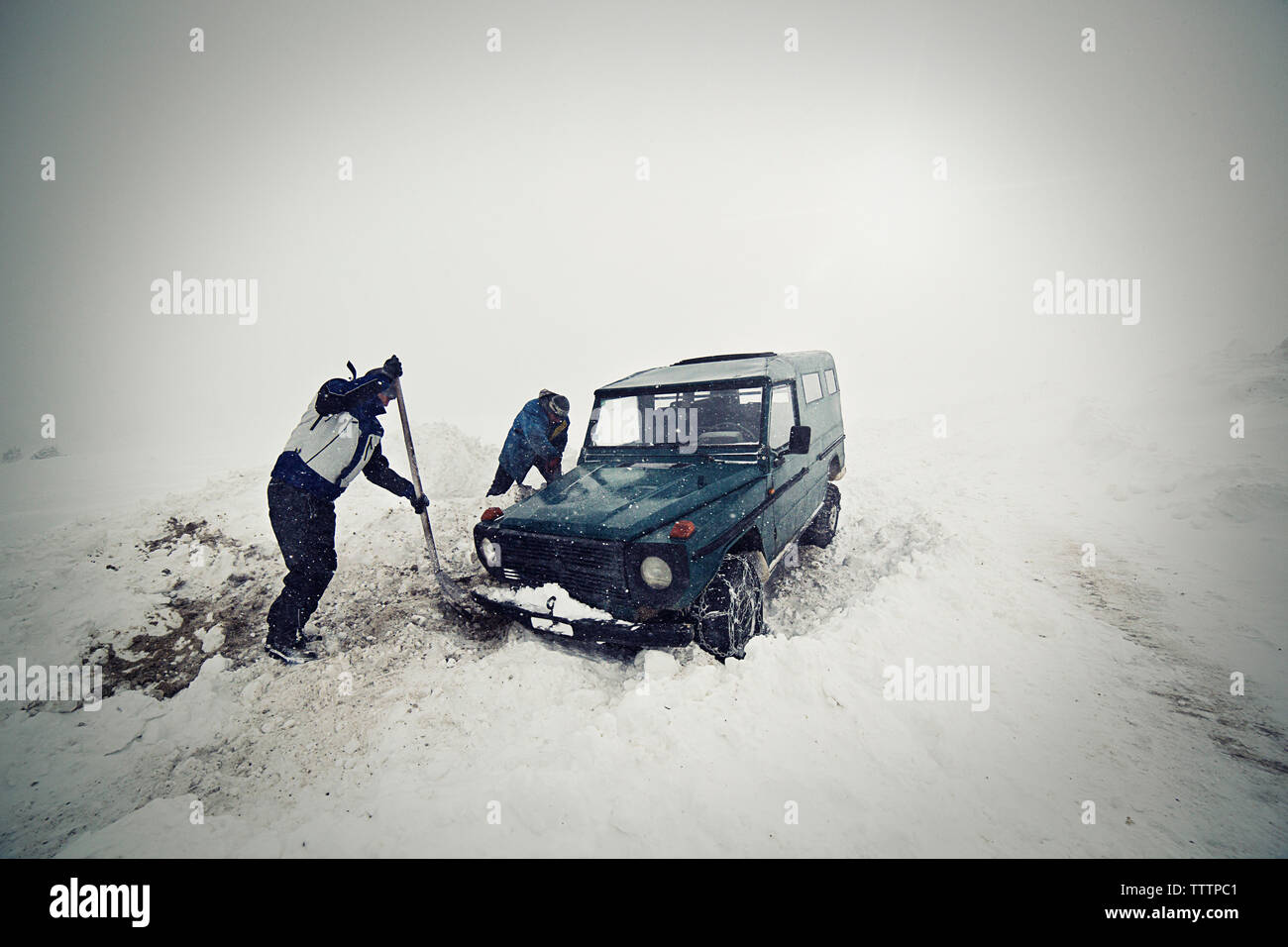 Men removing snow with shovel by car Stock Photo