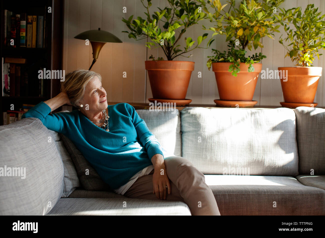 Thoughtful woman sitting on sofa at home Stock Photo