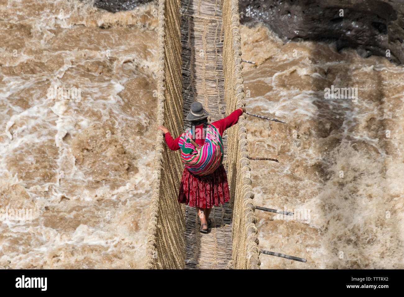 Quechua woman crossing Queshuachaca (Q'eswachaka) rope bridge, one of