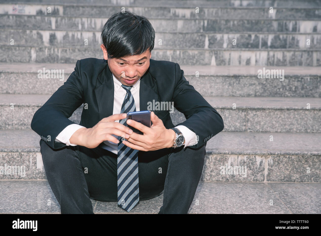 Asian businessmen with headaches or migraines at the city hall after work Images of young businessmen who are tired, stress, crisis, depression, failu Stock Photo