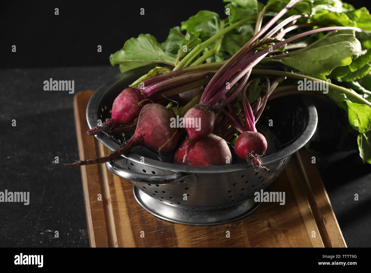 Bunch of fresh beets in a colander on wooden board Stock Photo