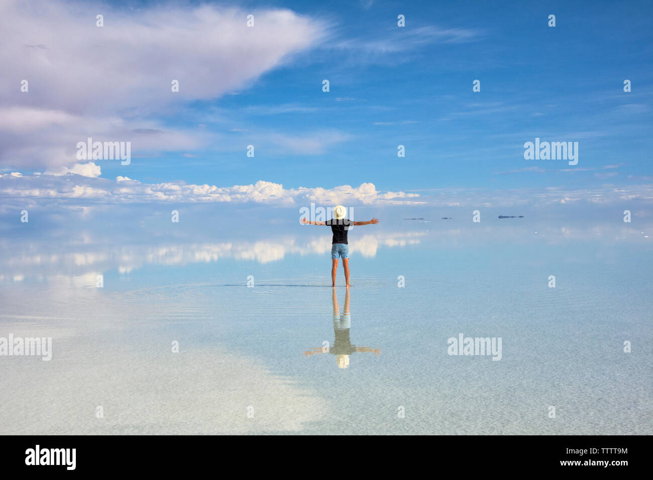 Tourist on the reflected surface of the salt flat, Salar de Uyuni, Potosi Department, Bolivia Stock Photo