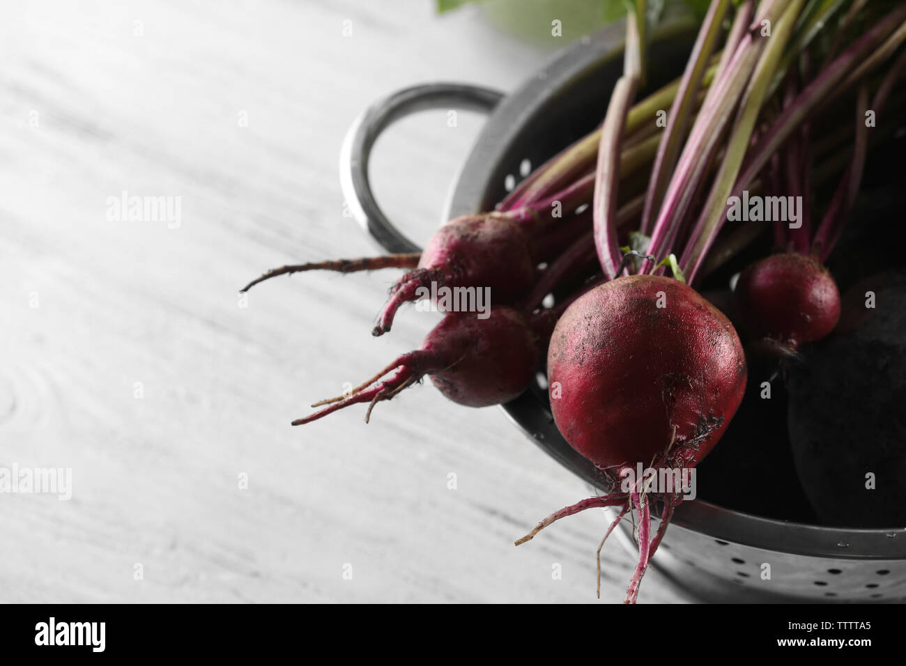 Bunch of fresh beets in a colander on light wooden background Stock Photo