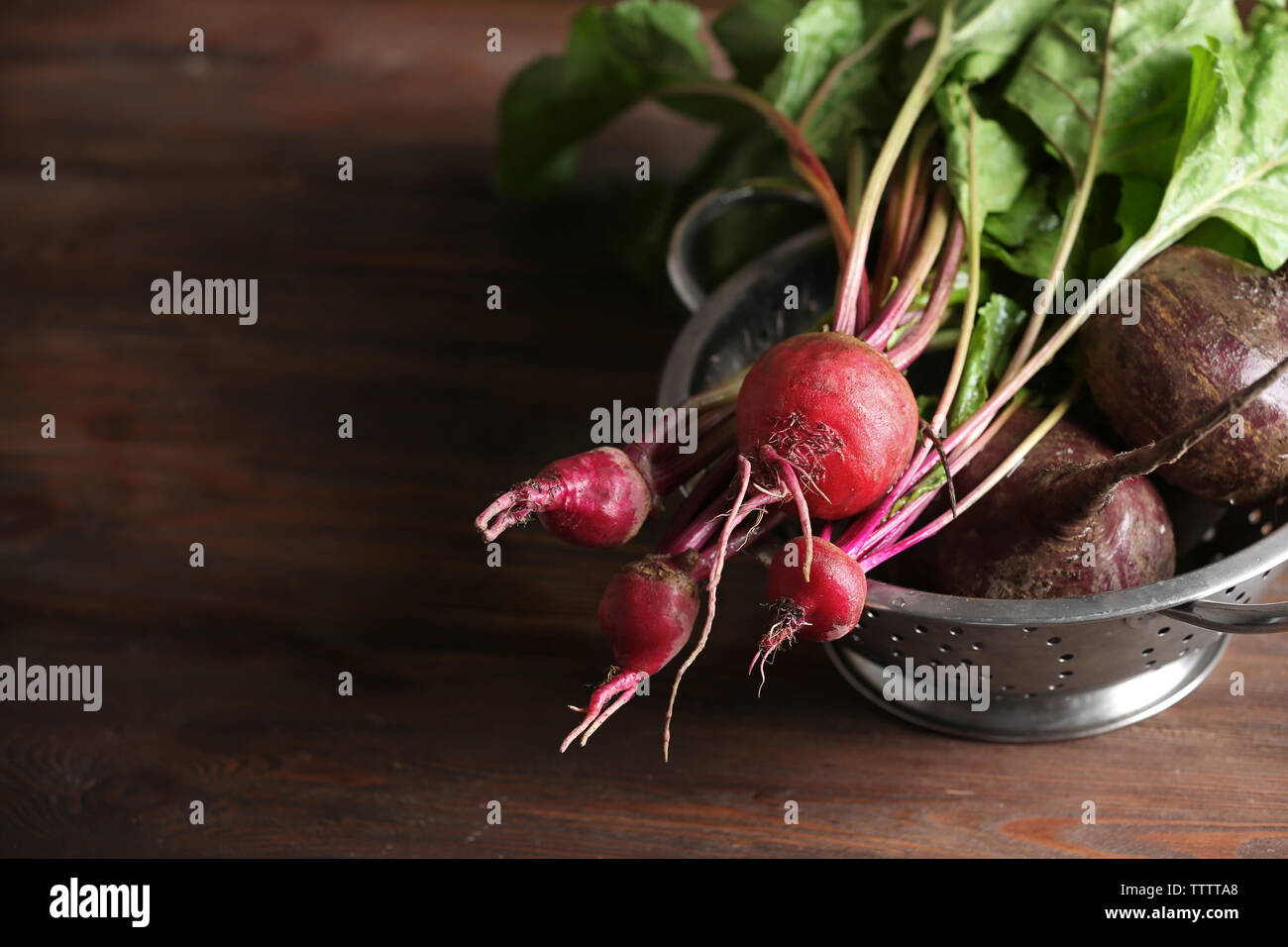 Bunch of fresh beets in a colander on wooden table Stock Photo