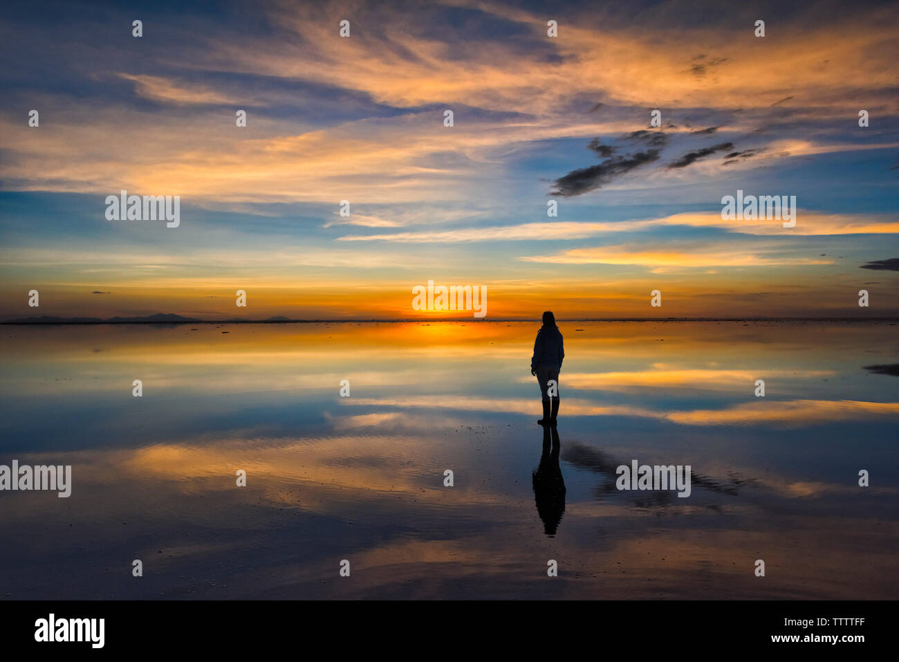 Tourist On The Reflected Surface Of The Salt Flat At Sunset Salar De tourist-on-the-reflected-surface-of-the-salt-flat-at-sunset-salar-de