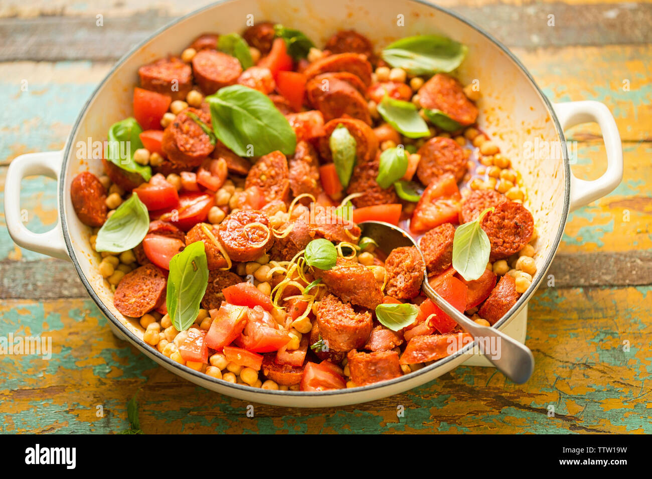 Fried chorizo sausage with chickpeas, tomatoes, lemon & basil Stock