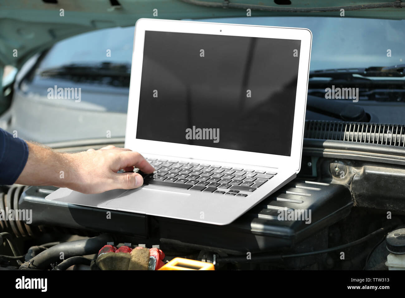 Mechanic using computer diagnostics while repairing car Stock Photo
