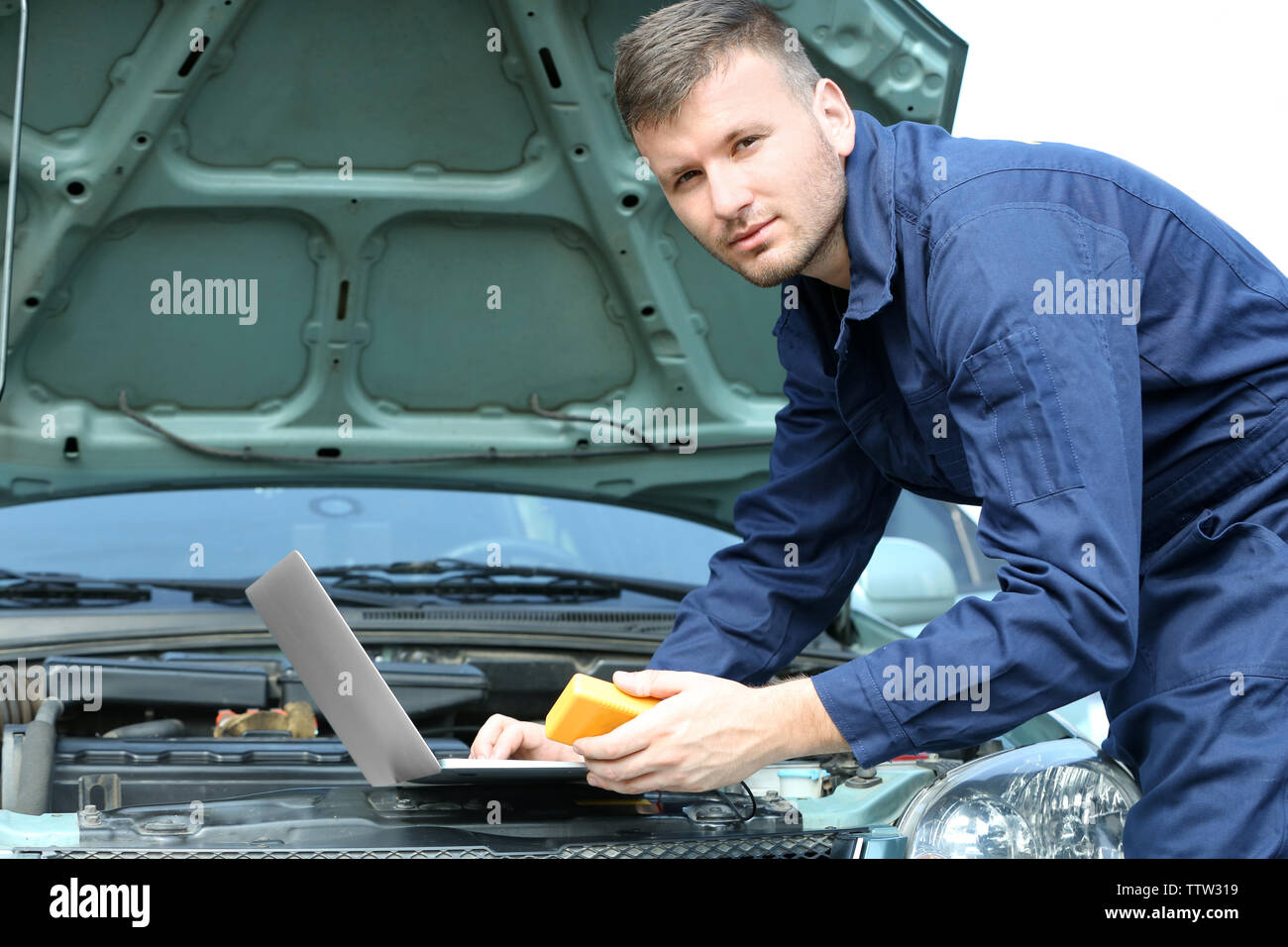 Mechanic using computer diagnostics while repairing car Stock Photo Alamy