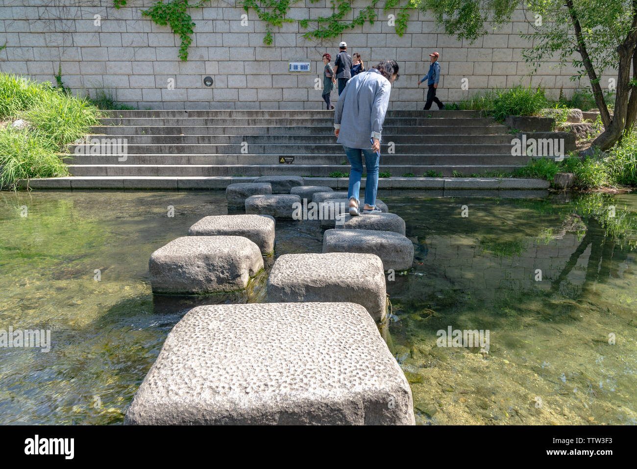 SEOUL, SOUTH KOREA - MAY 31, 2019: One woman is crossing the Cheonggyecheon stream, using stepping stones Stock Photo