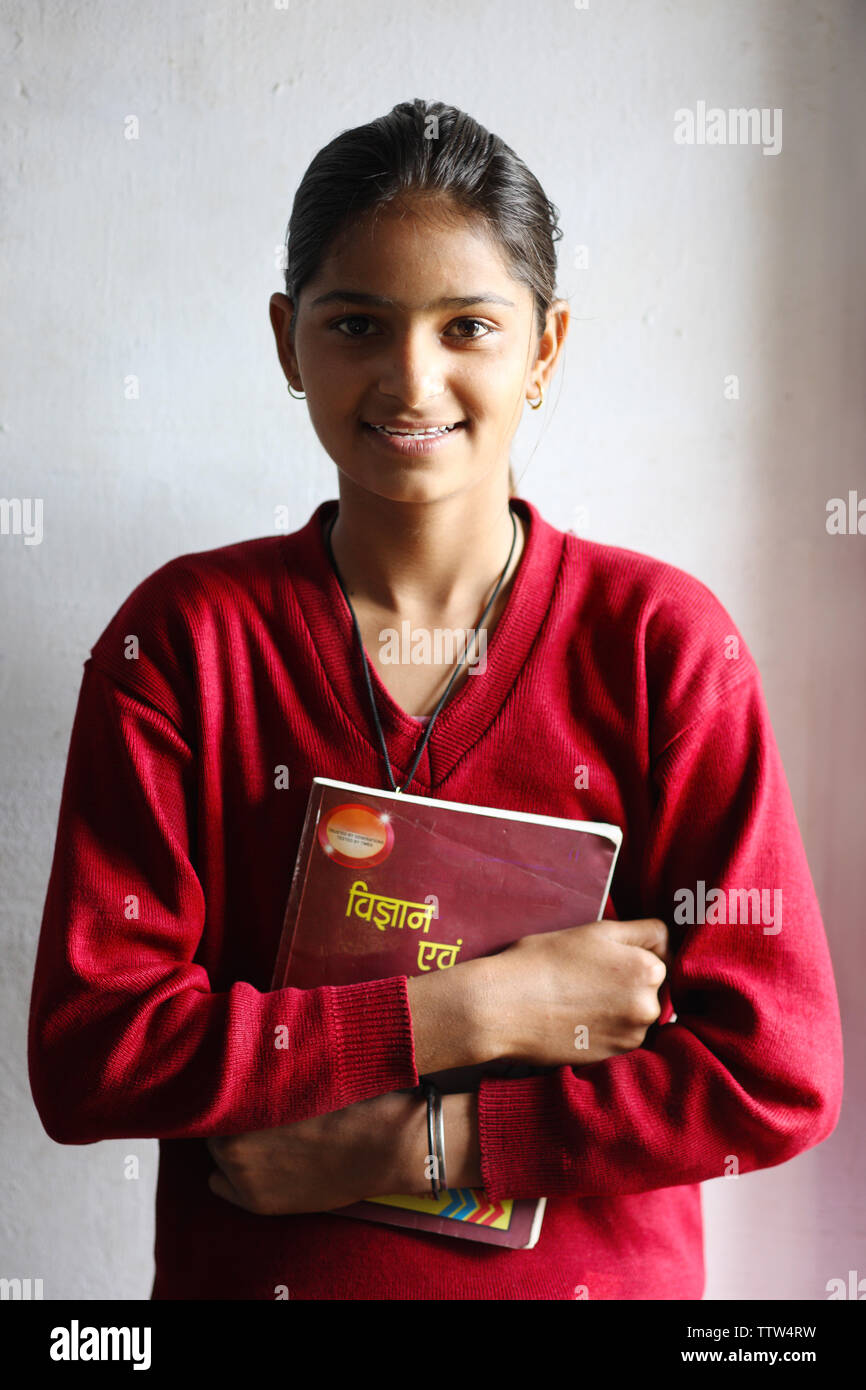 Indian schoolgirl holding a book and smiling Stock Photo - Alamy