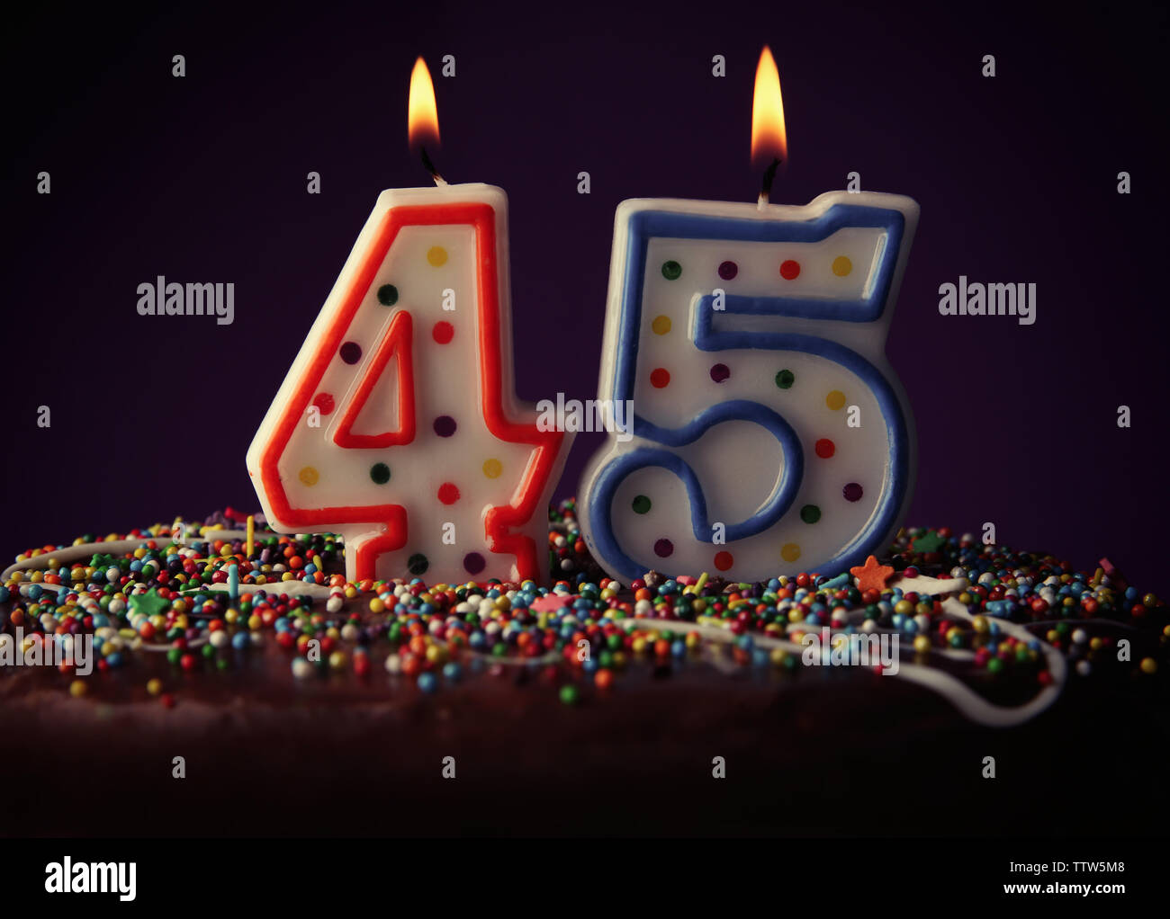 Birthday cake with burning candles on dark background Stock Photo - Alamy