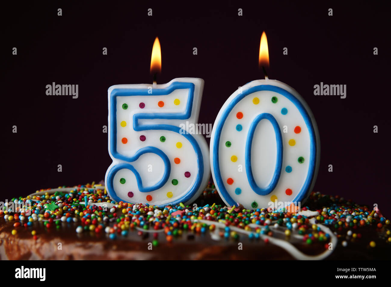 Birthday cake with burning candles on dark background Stock Photo - Alamy