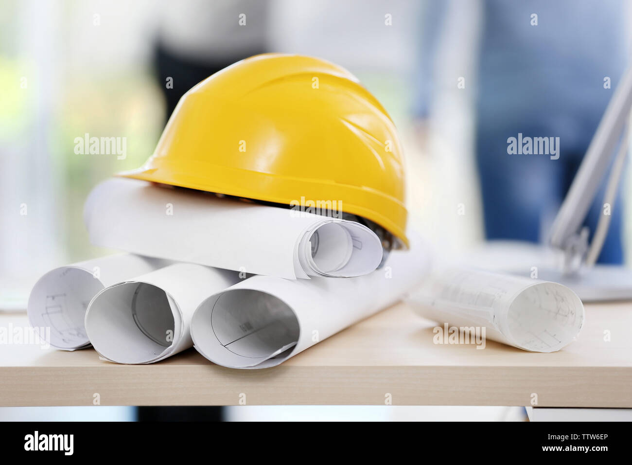 Helmet with blueprints on table, closeup Stock Photo - Alamy