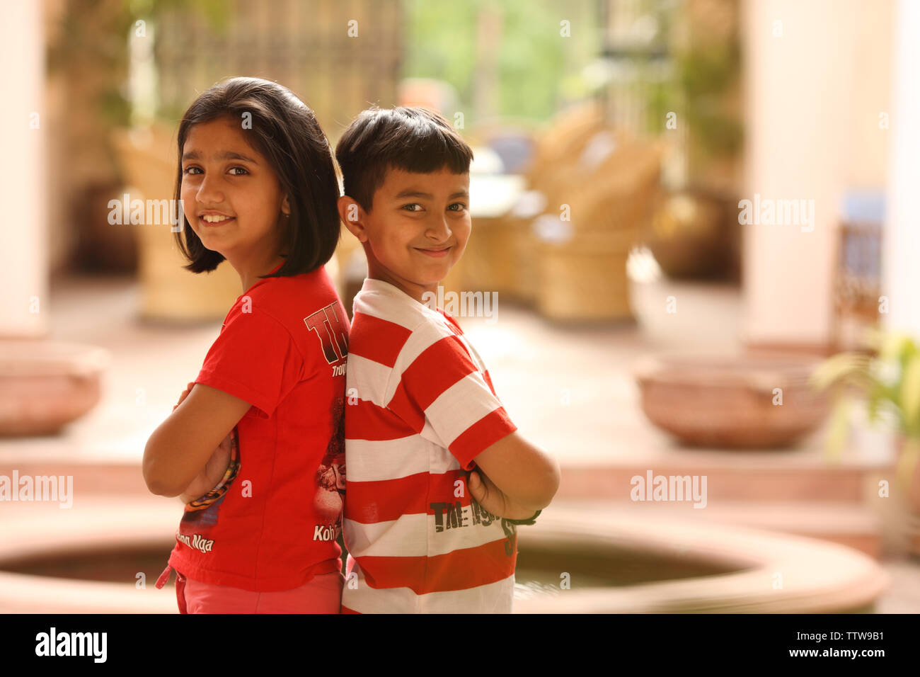 Portrait of a boy and a girl standing back to back Stock Photo - Alamy