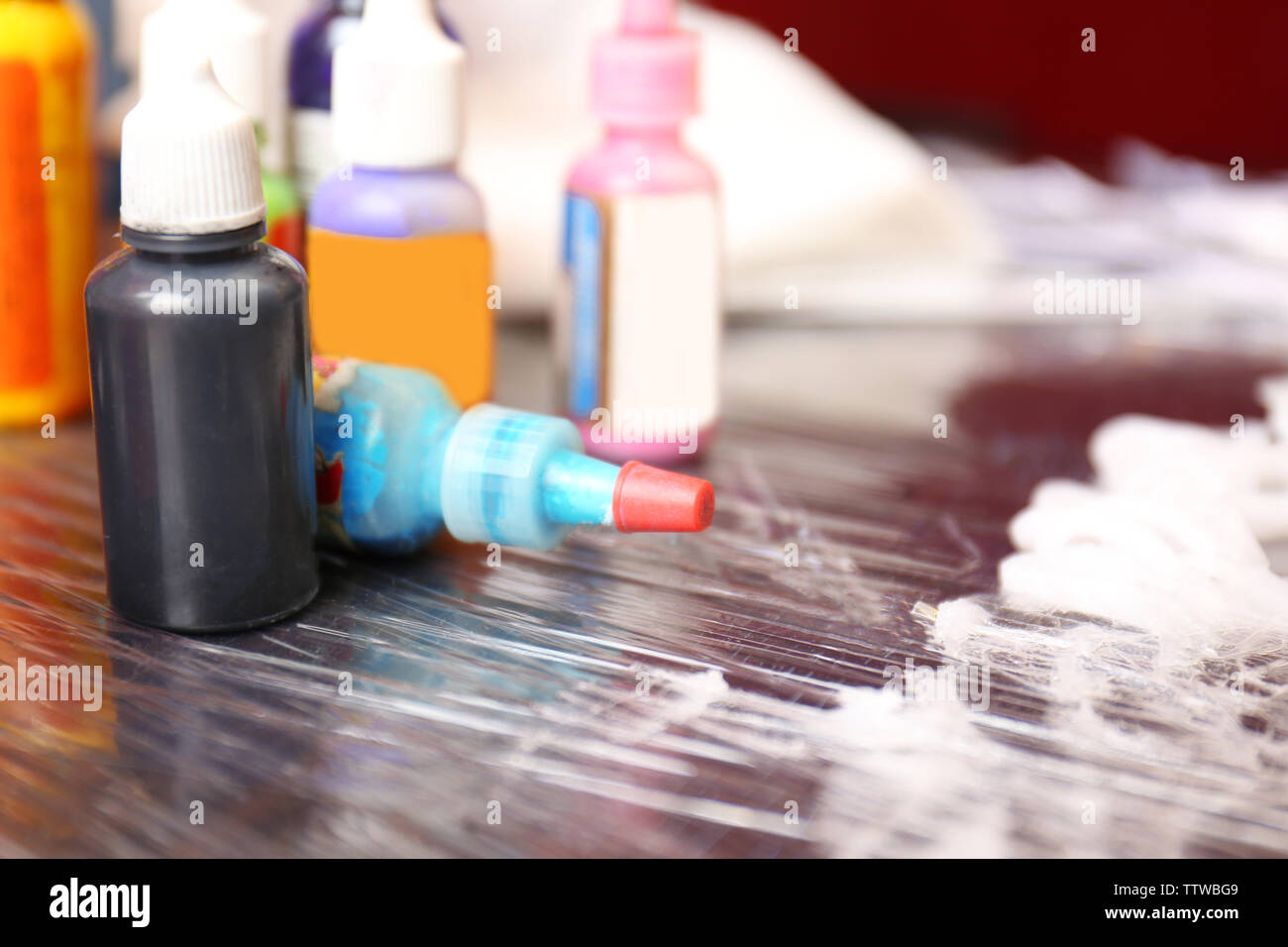 Bottles with tattoo colorful inks and petroleum jelly on wooden table, close up view Stock Photo