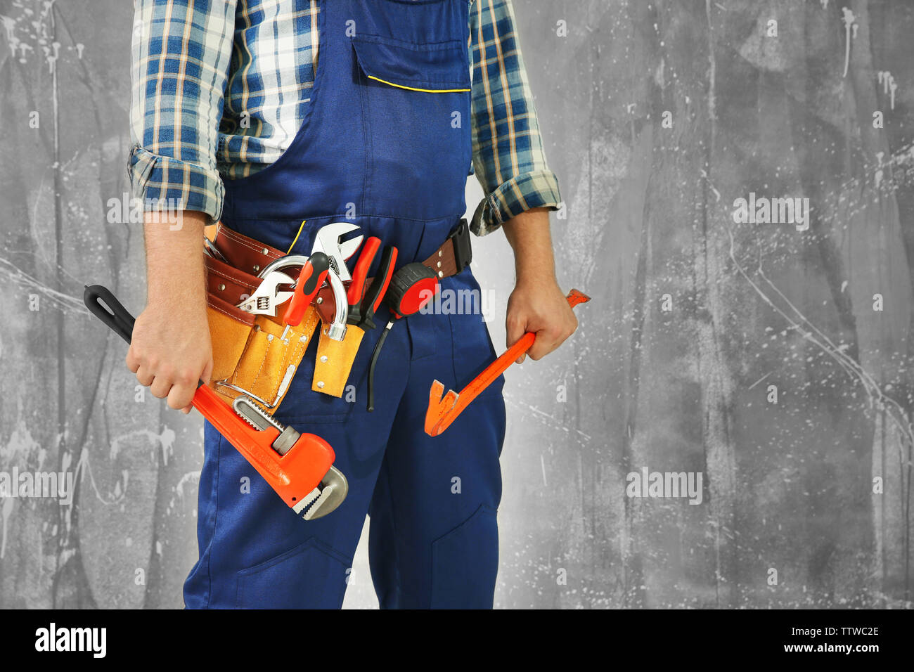 Plumber with tools against grunge background, close up view Stock Photo