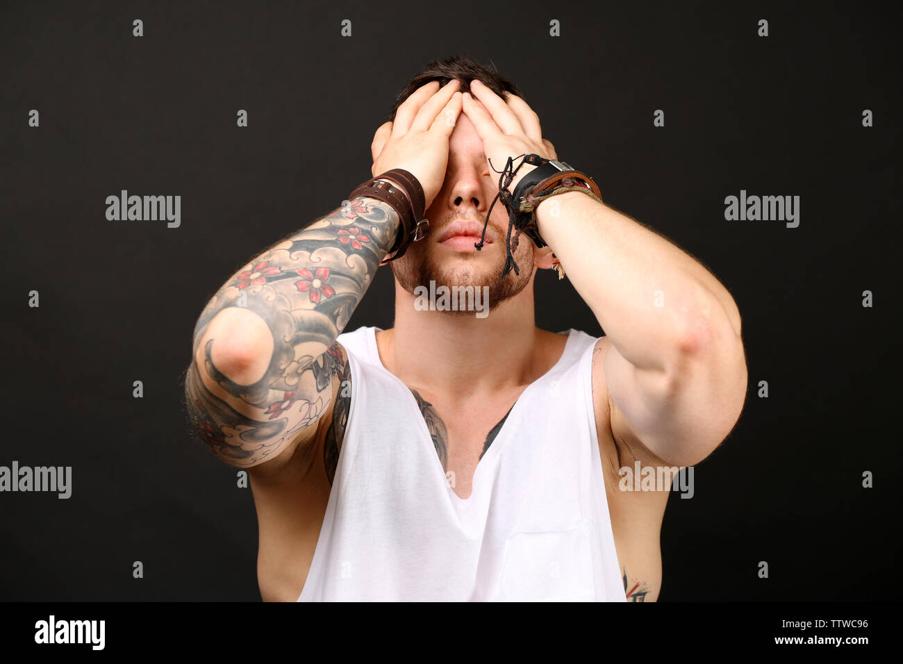 Young tattooed man posing on dark background Stock Photo