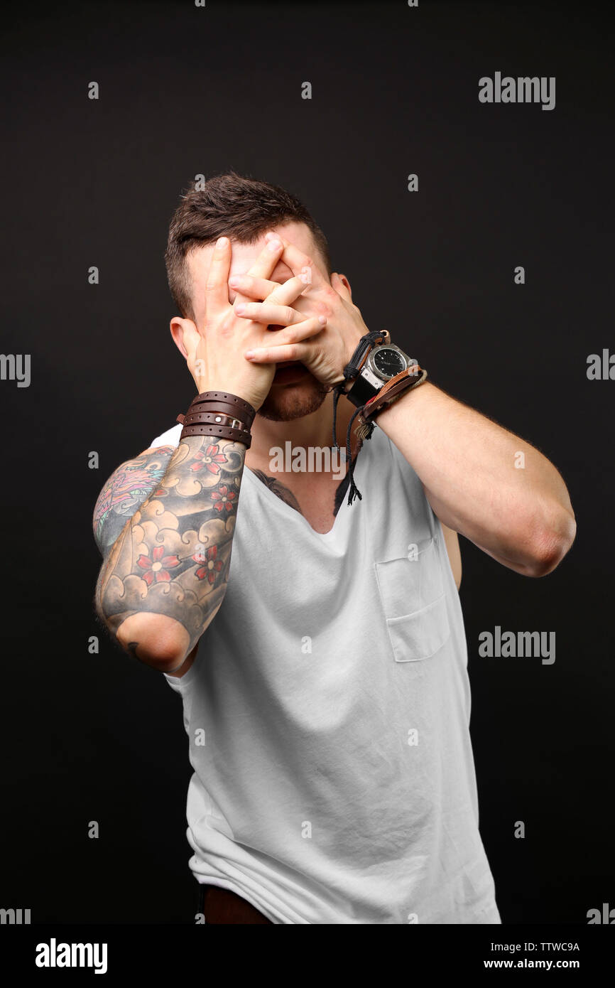 Young tattooed man posing on dark background Stock Photo