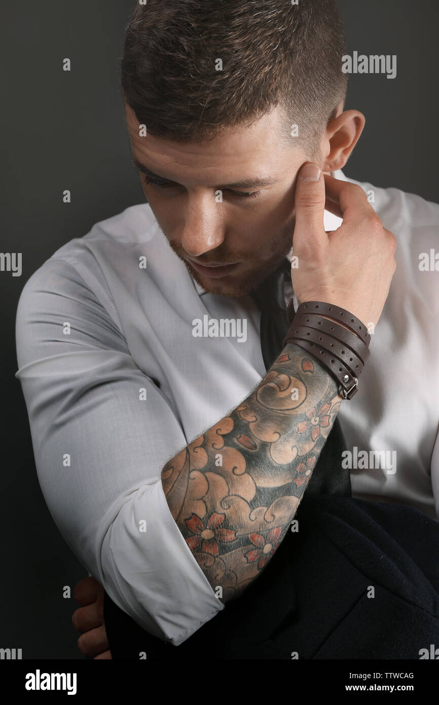 Young tattooed man posing on dark background Stock Photo