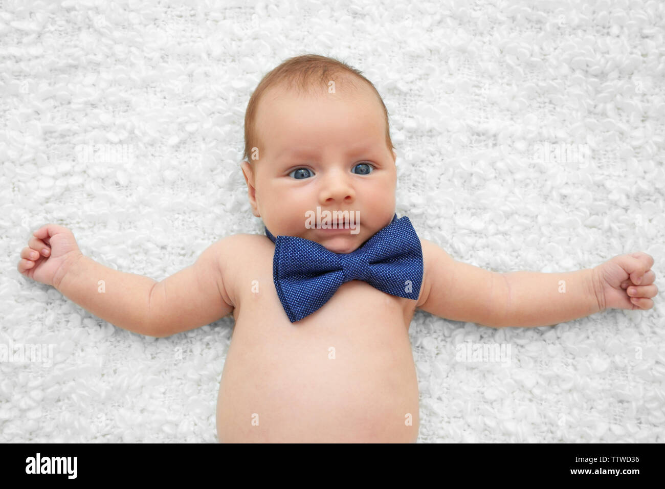 Cute baby with bow tie lying on white bedspread Stock Photo Alamy