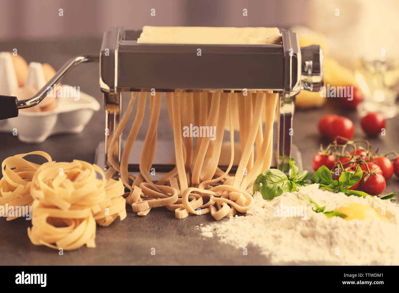 https://c8.alamy.com/comp/TTWDM1/making-tagliatelle-with-pasta-machine-on-kitchen-table-TTWDM1.jpg