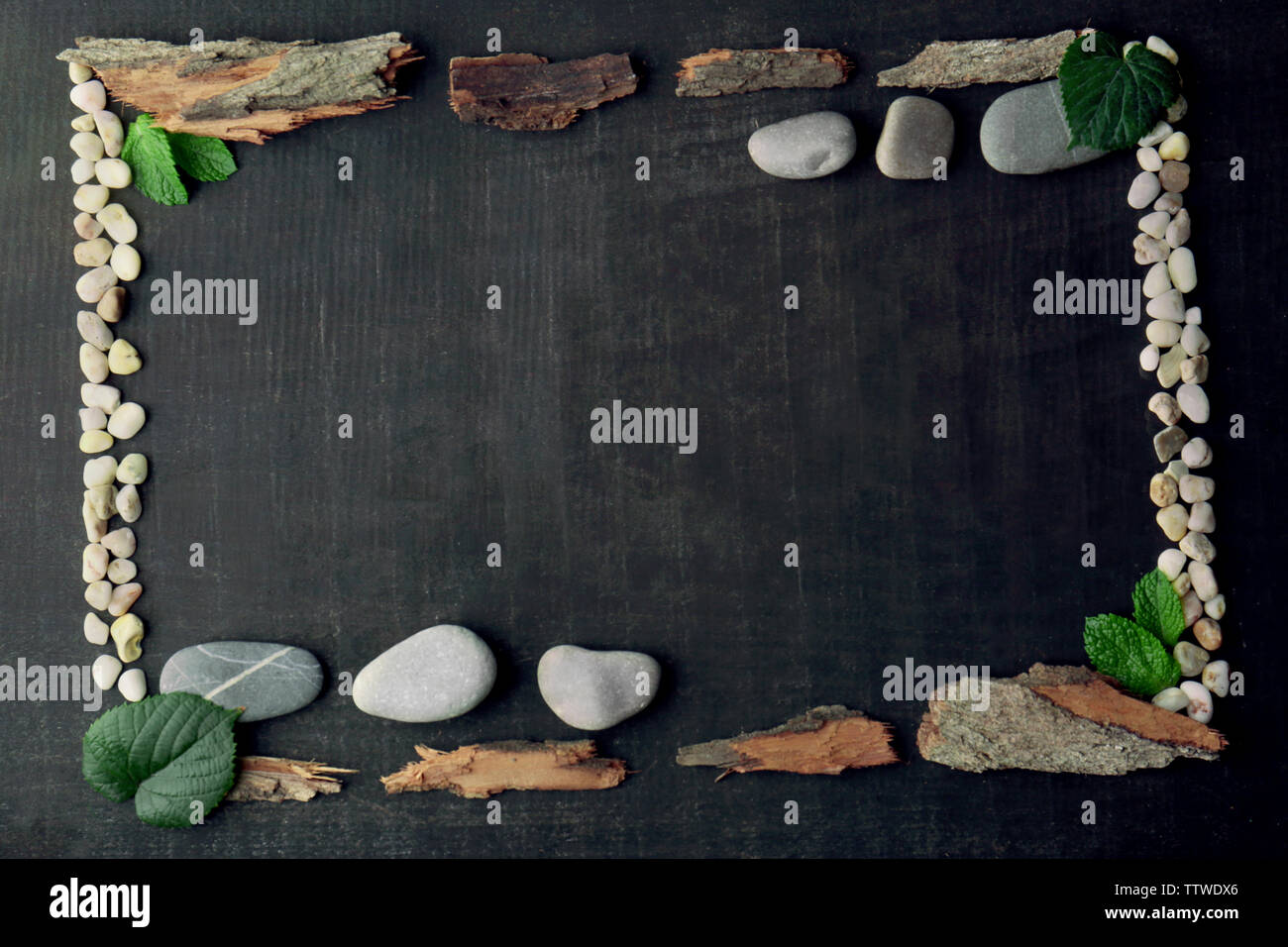 Rectangular frame made of leaves, pebbles and bark on dark background Stock Photo