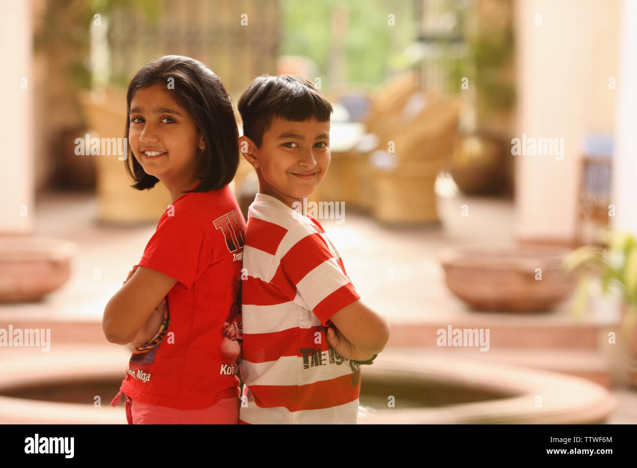 Portrait of a boy and a girl standing back to back Stock Photo - Alamy
