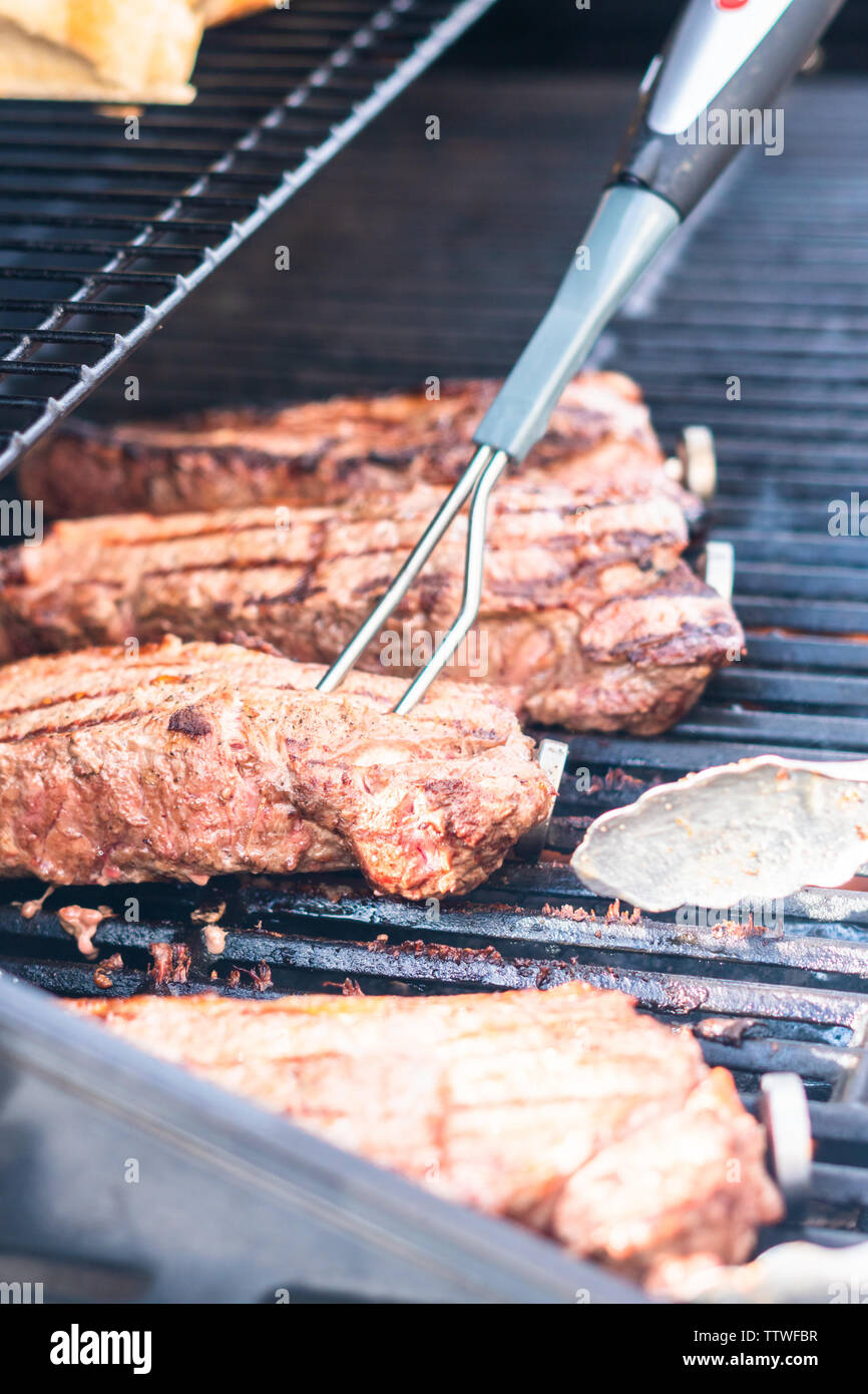 Grilling New York strip steak on outdoor gas grill Stock Photo Alamy