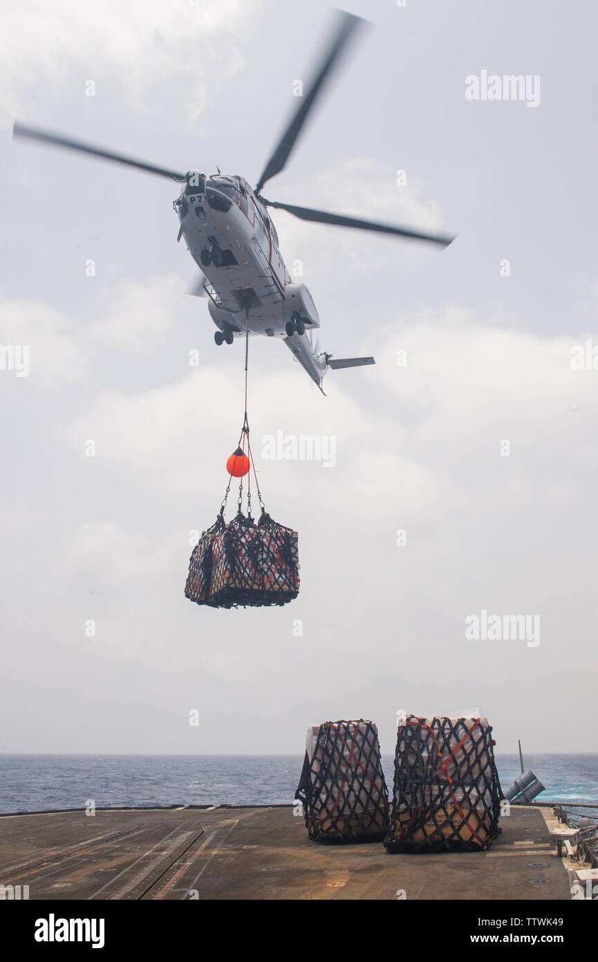 190614-N-DS741-0109 ARABIAN SEA (June 14, 2019) A helicopter assigned to the dry cargo and ammunition ship USNS Cesar Chavez (T-AKE 14) prepares to drop cargo onto the flight deck of the Ticonderoga-class guided-missile cruiser USS Leyte Gulf (CG 55) during a vertical replenishment. Leyte Gulf is deployed to the U.S. 5th Fleet areas of operations in support of naval operations to ensure maritime stability and security in the Central Region, connecting the Mediterranean and Pacific through the Western Indian Ocean and three strategic choke points. (U.S. Navy photo by Mass Communication Speciali Stock Photo