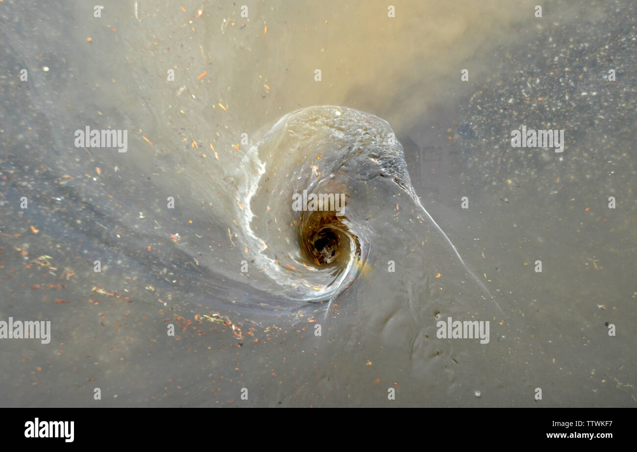 Vortex in water over a drain after heavy rainfall. Stock Photo