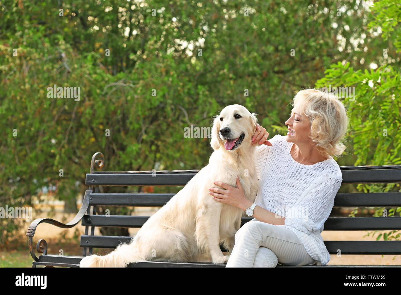 Senior woman sitting on bench with dog Stock Photo - Alamy