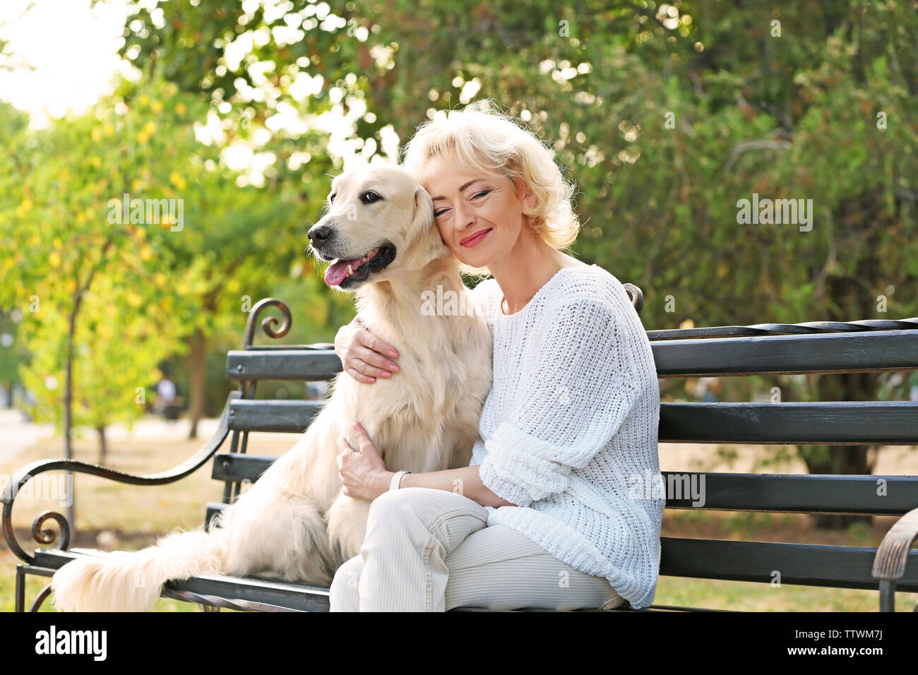 Senior woman sitting on bench with dog Stock Photo - Alamy