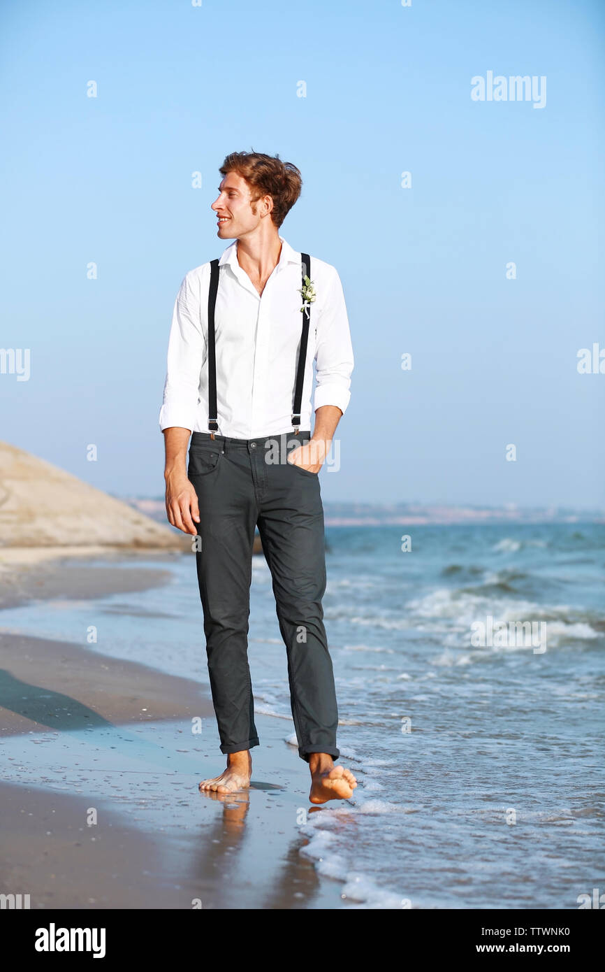 Young man walking along seashore Stock Photo - Alamy