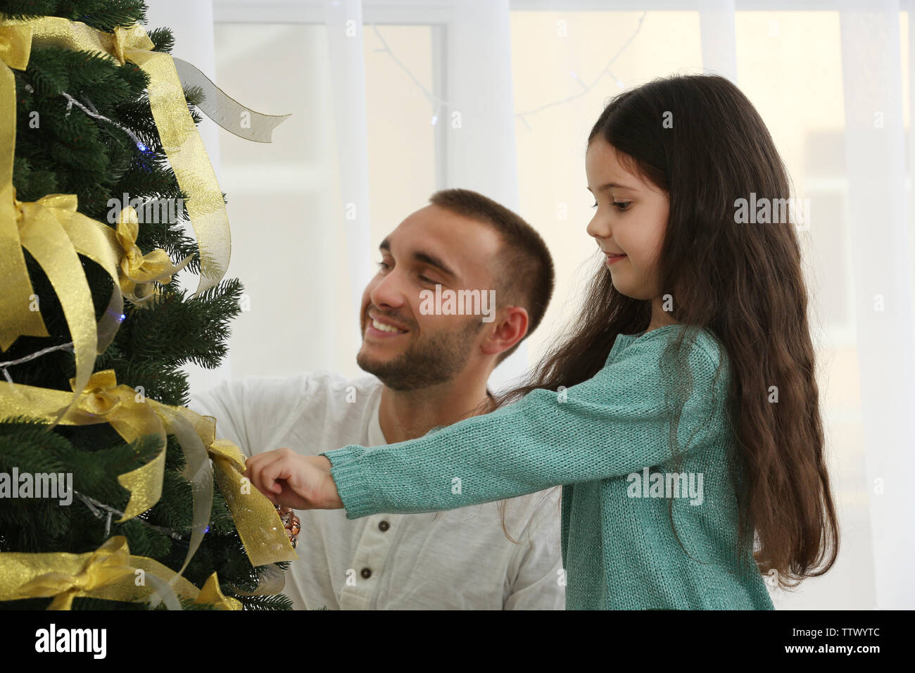 Little girl decorating Christmas tree with her father Stock Photo - Alamy